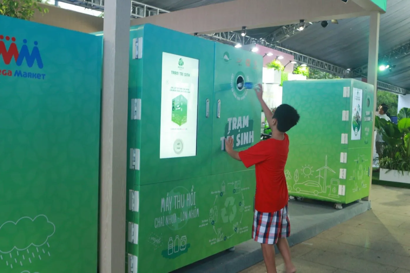 Một bé trai đang bỏ chai nhựa vào thùng